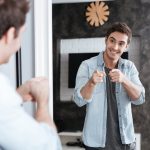 Smiling young man pointing fingers at his mirror reflection