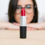 Beautiful woman looking on the lipstick. Focus on lipstick